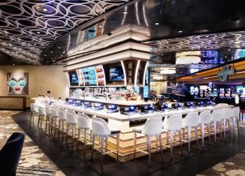 A large casino bar with white chairs and silver finishes