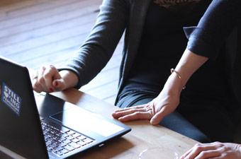 Two people leaning over a laptop 