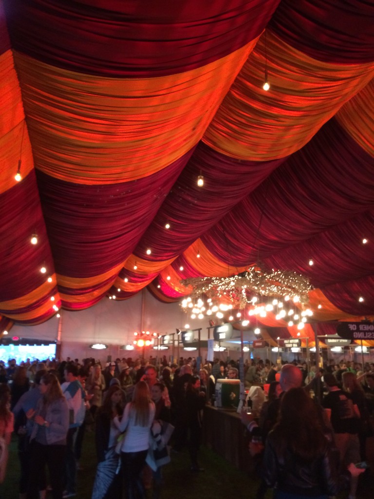 People gather in a large tent with red ceiling